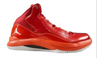 Orange ankle high basketball shoes with a white jump man logo on the back heel of the shoe.