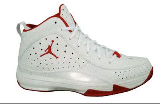 Ankle high basketball shoes that are all white with a red lining around the ankle. A red jump man logo is on the side of the shoe.
