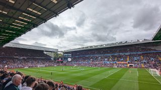 My view of the Brighton vs Aston Villa Premier League football game at Villa Park from the away end. The Brighton players wearing their home kit of blue and white striped shirts, blue shorts and blue socks, are getting ready to kick-off from right to left against Aston Villa in their home kit of claret and blue shirts, white shorts and blue socks.