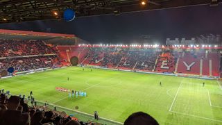View of the pitch from the upper tier of the west stand at The Valley. The players are lined parallel to the touchline having just walked out the tunnel.