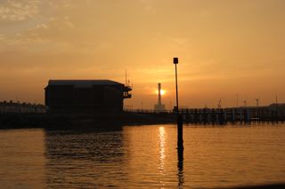 Sun rising behind Shoreham power station and Shoreham lifeboat station. The sunrise is reflecting off the sea below.