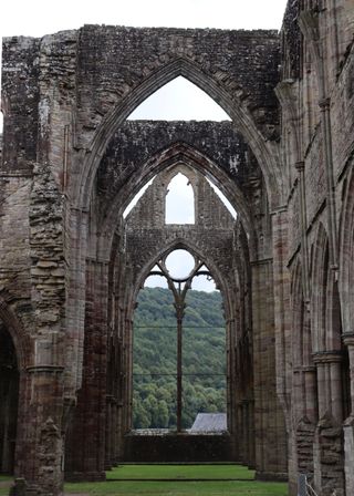 Archways aligning with windows inside Tintern Abbey.
