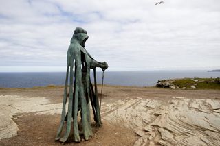 An 8 foot tall bronze statue of King Arthur on a clifftop at Tintagel Castle.